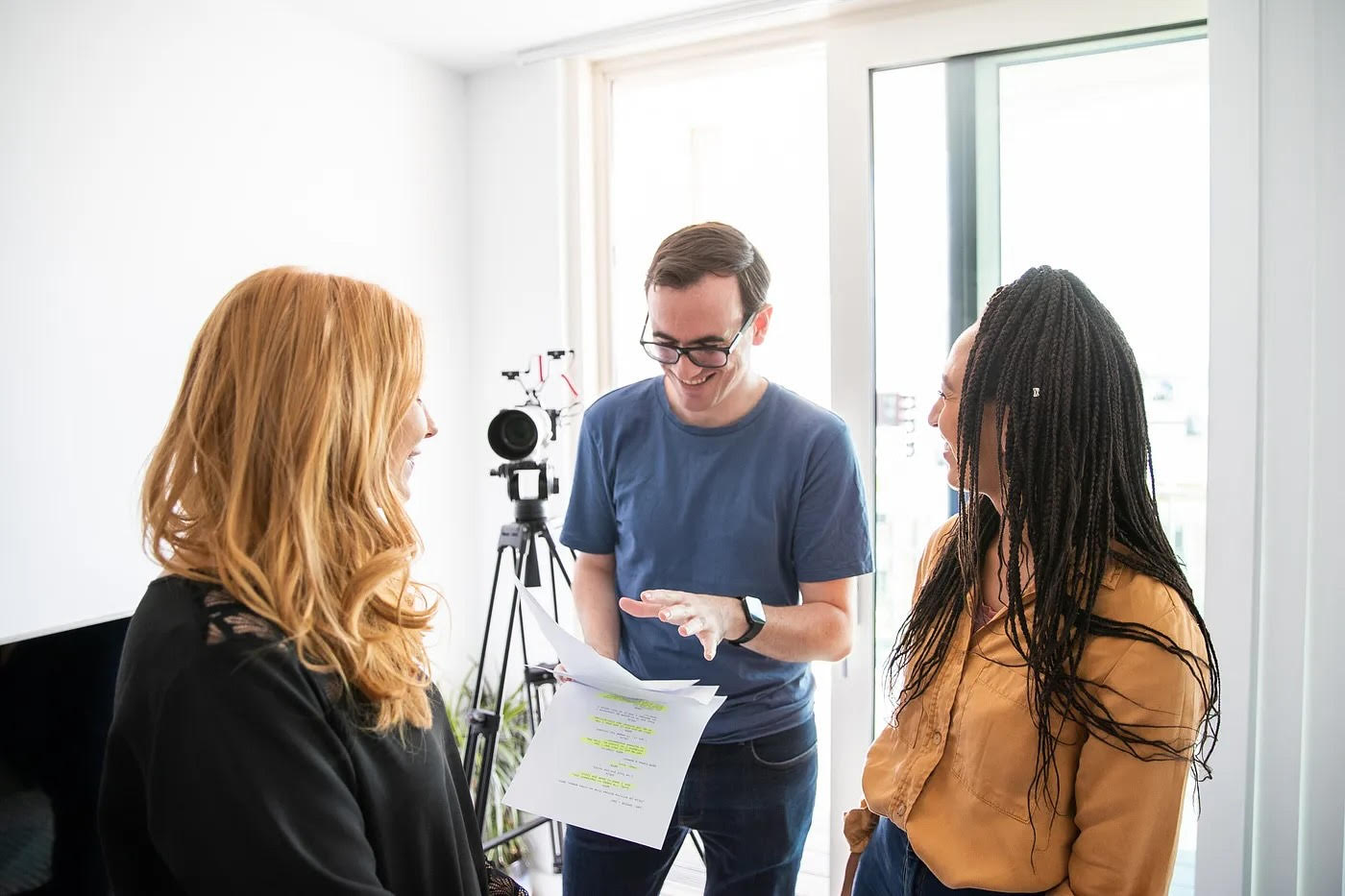 Daniel Johnson holding a script on a film set, directing two female actors