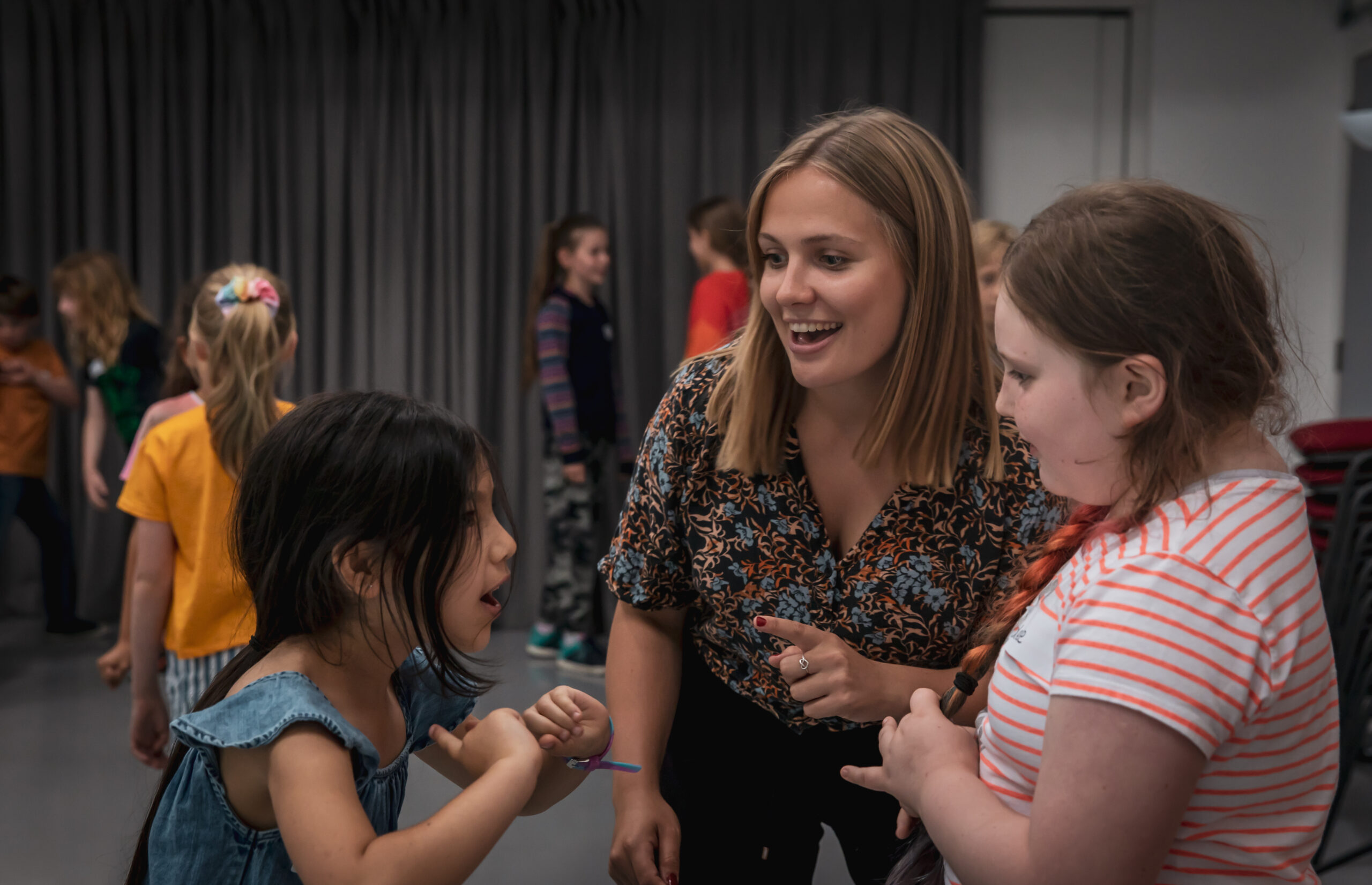 A drama teacher helping two young performers doing a drama game