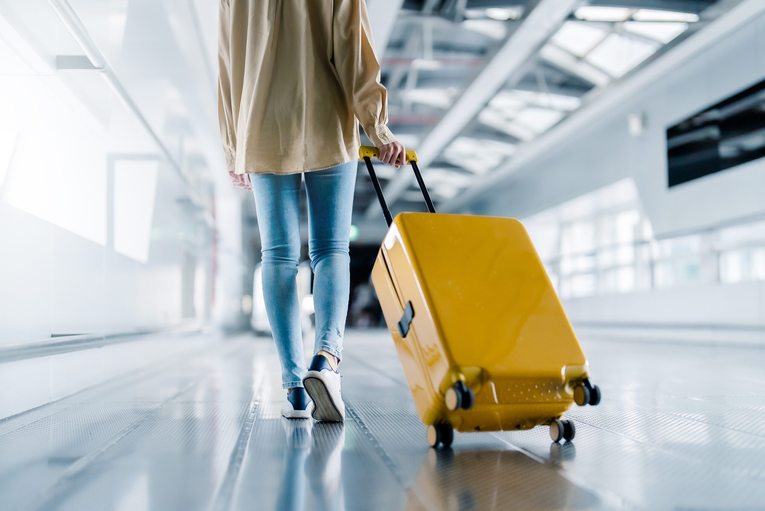 Woman pulling a yellow suitcase through an airport