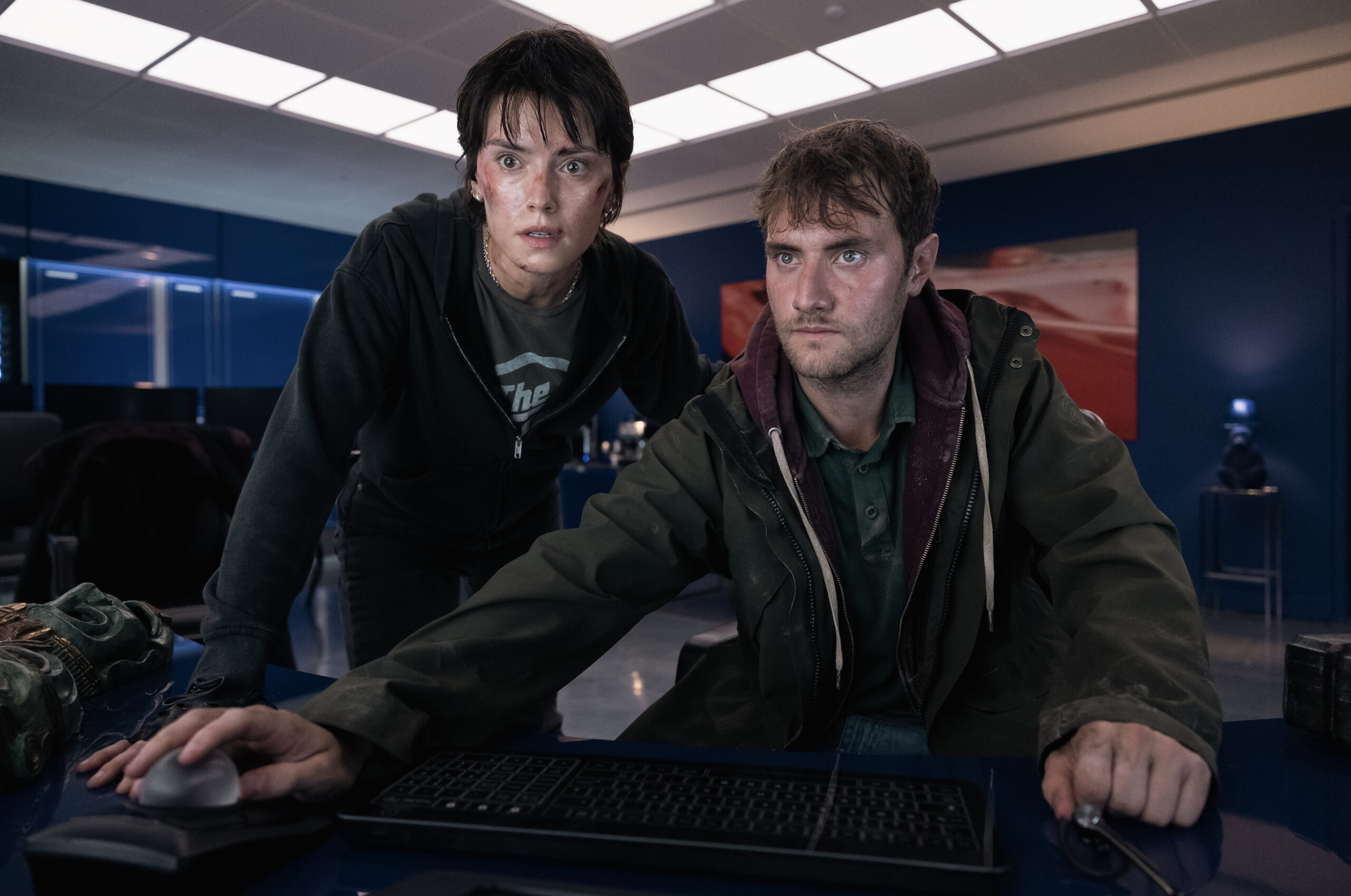 Daisy Ridley and Matthew Tuck in 'Cleaner' looking serious using a computer at a desk