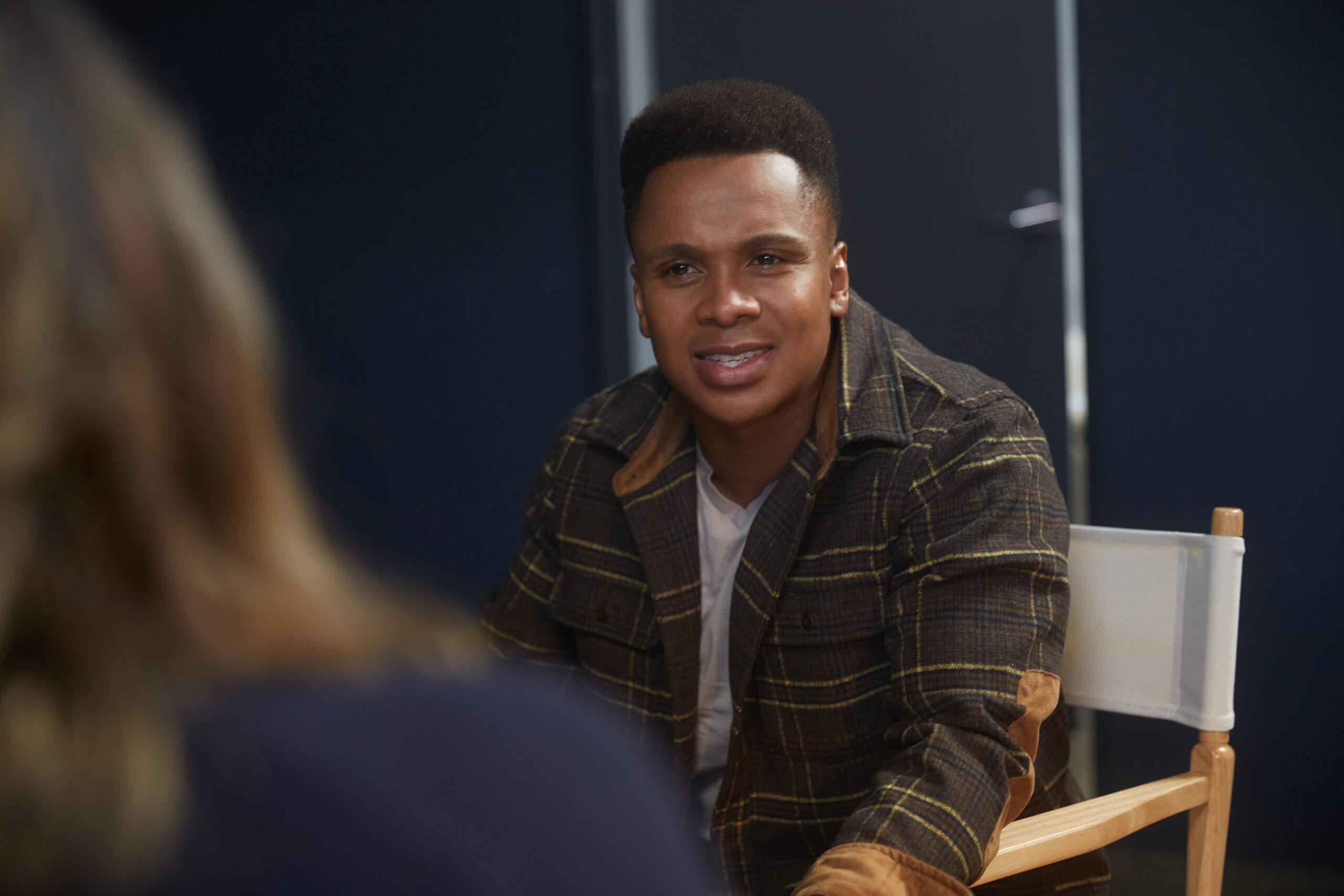 Young man sitting in a chair having a serious conversation with someone just off shot